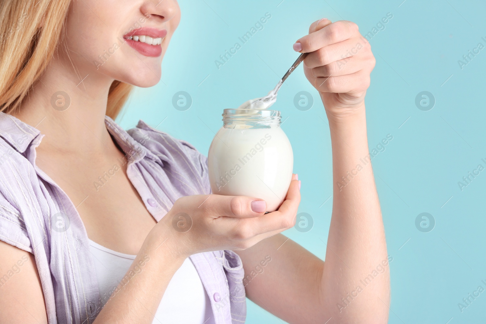 Photo of Young woman with yogurt on color background