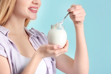 Young woman with yogurt on color background