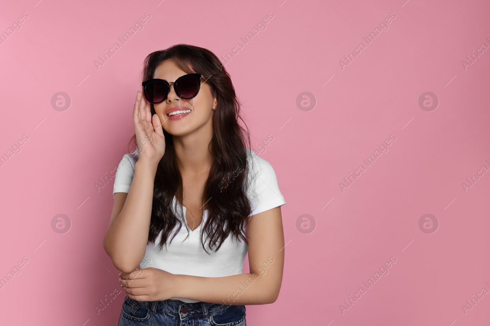 Photo of Happy beautiful woman with stylish sunglasses on pink background, space for text
