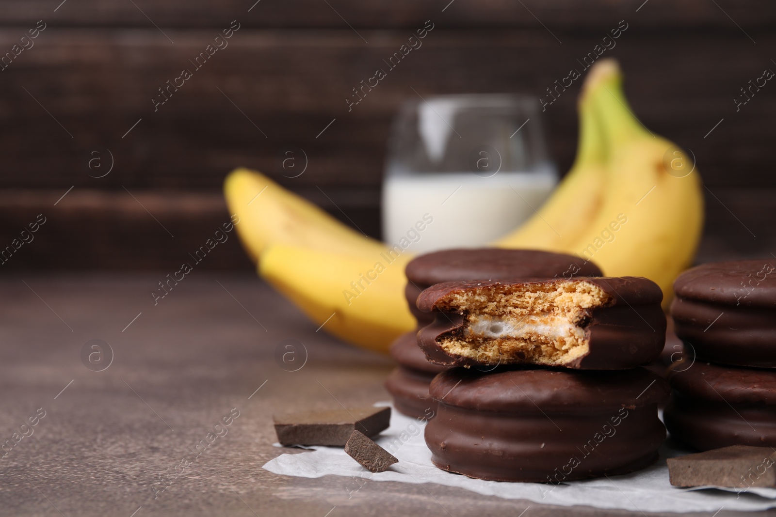 Photo of Tasty banana choco pies and pieces of chocolate on textured table, closeup. Space for text