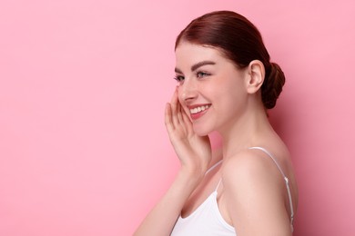 Portrait of smiling woman on pink background. Space for text