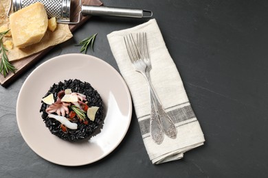 Photo of Delicious black risotto with seafood and cheese served on grey table, flat lay