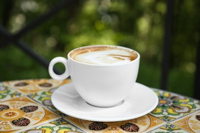 Photo of Cup of aromatic coffee on beautiful table in cafe outdoors