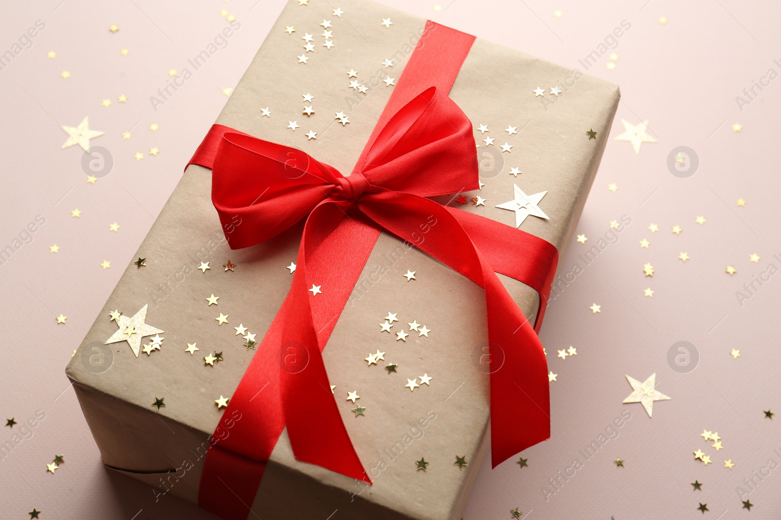 Photo of Gift box and confetti stars on light background, closeup. Christmas celebration