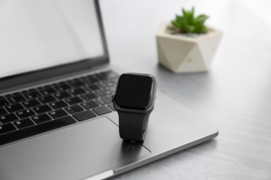 Photo of Stylish smart watch and laptop on grey table, closeup