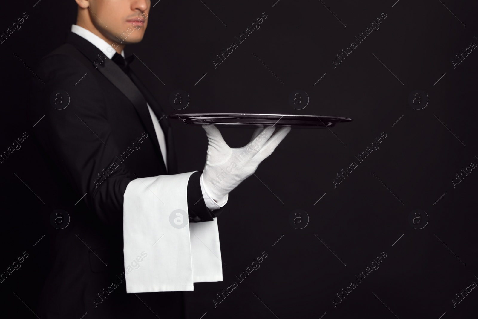 Photo of Butler with tray on black background, closeup. Space for text