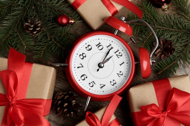 Flat lay composition with Christmas gifts and alarm clock on wooden table. Boxing day