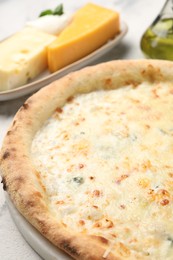 Photo of Delicious cheese pizza, oil and different kinds of cheese on table, closeup