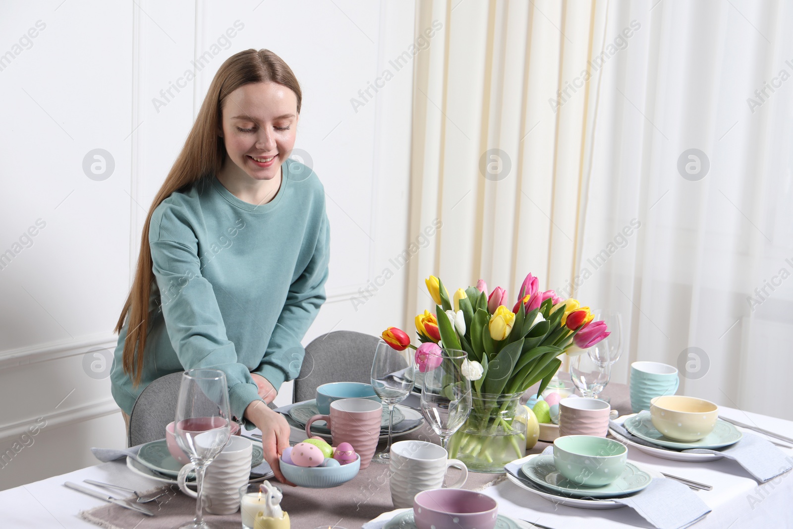 Photo of Woman setting table for festive Easter dinner at home