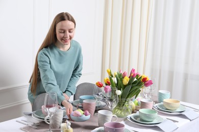 Woman setting table for festive Easter dinner at home