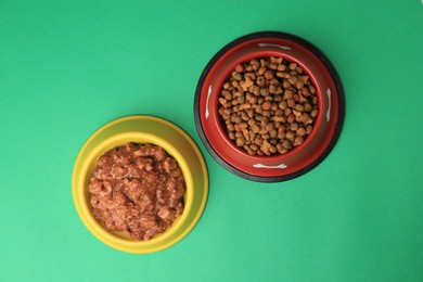 Photo of Dry and wet pet food in feeding bowls on green background, flat lay