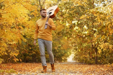 Photo of Young man with guitar in autumn park