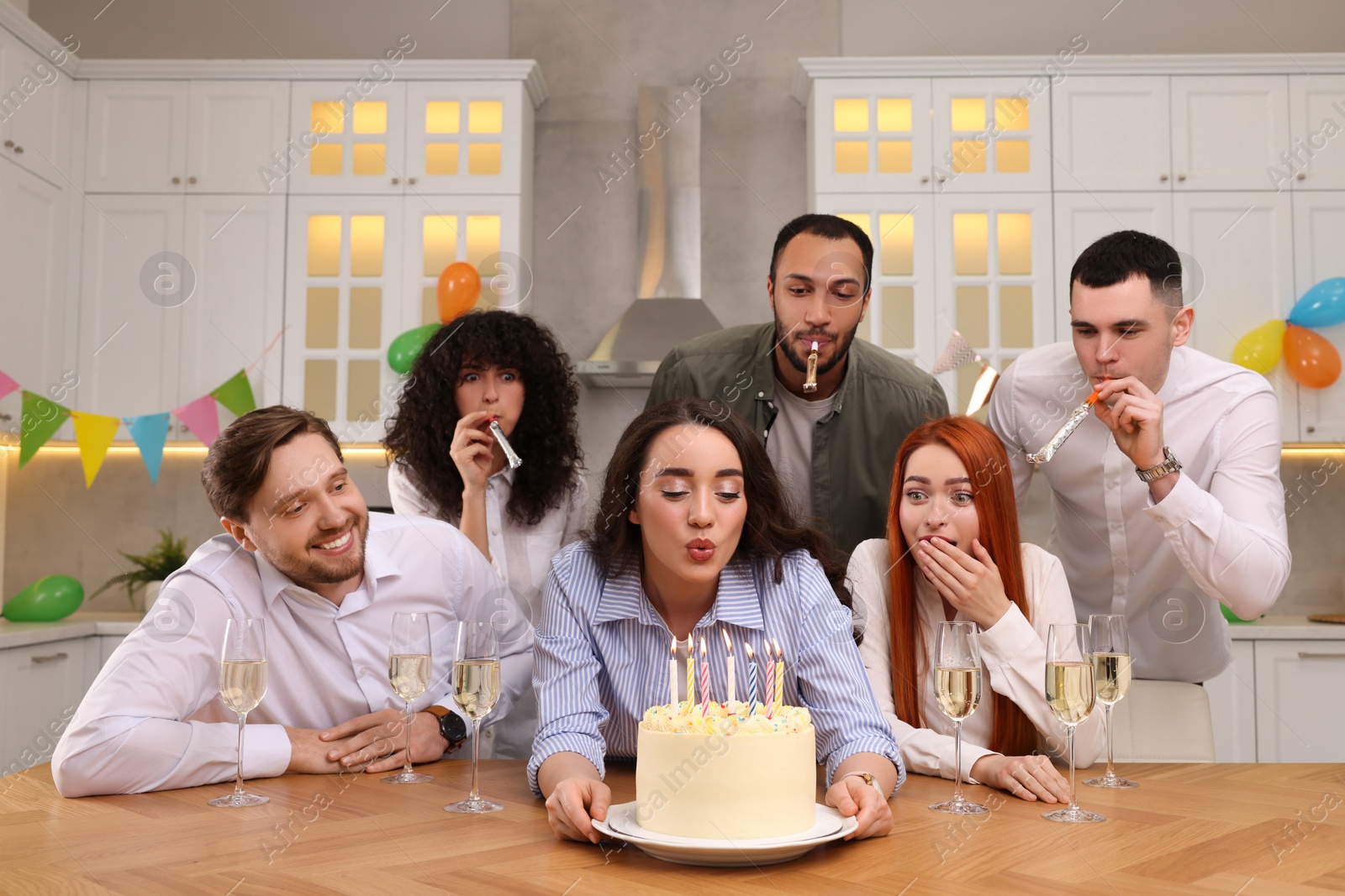 Photo of Happy friends with tasty cake celebrating birthday in kitchen