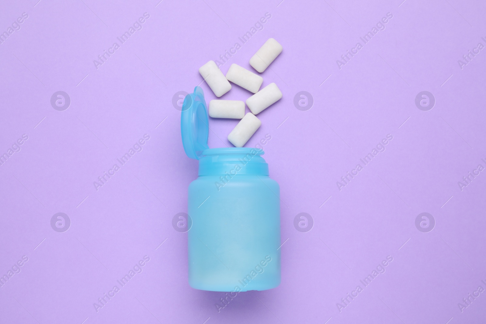 Photo of Jar with chewing gums on lilac background, flat lay