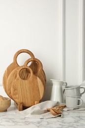 Photo of Wooden cutting boards, spoons and dishware on white marble table
