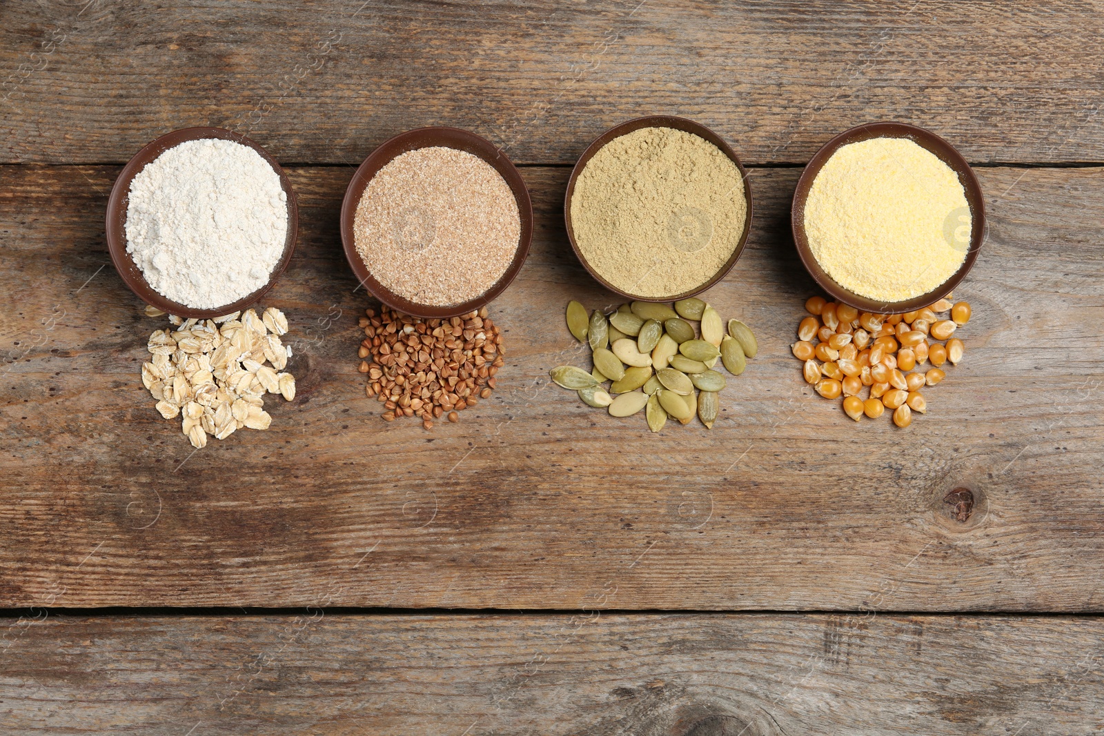 Photo of Flat lay composition with different types of flour and seeds on wooden background. Space for text