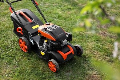 Modern lawn mower on green grass in garden