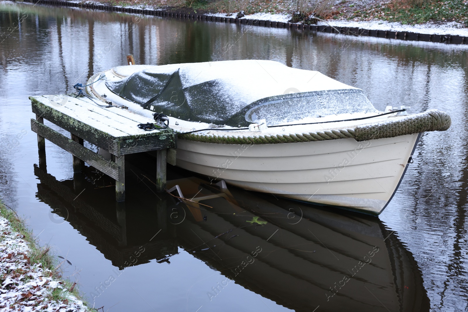 Photo of Water canal with moored boat on winter day