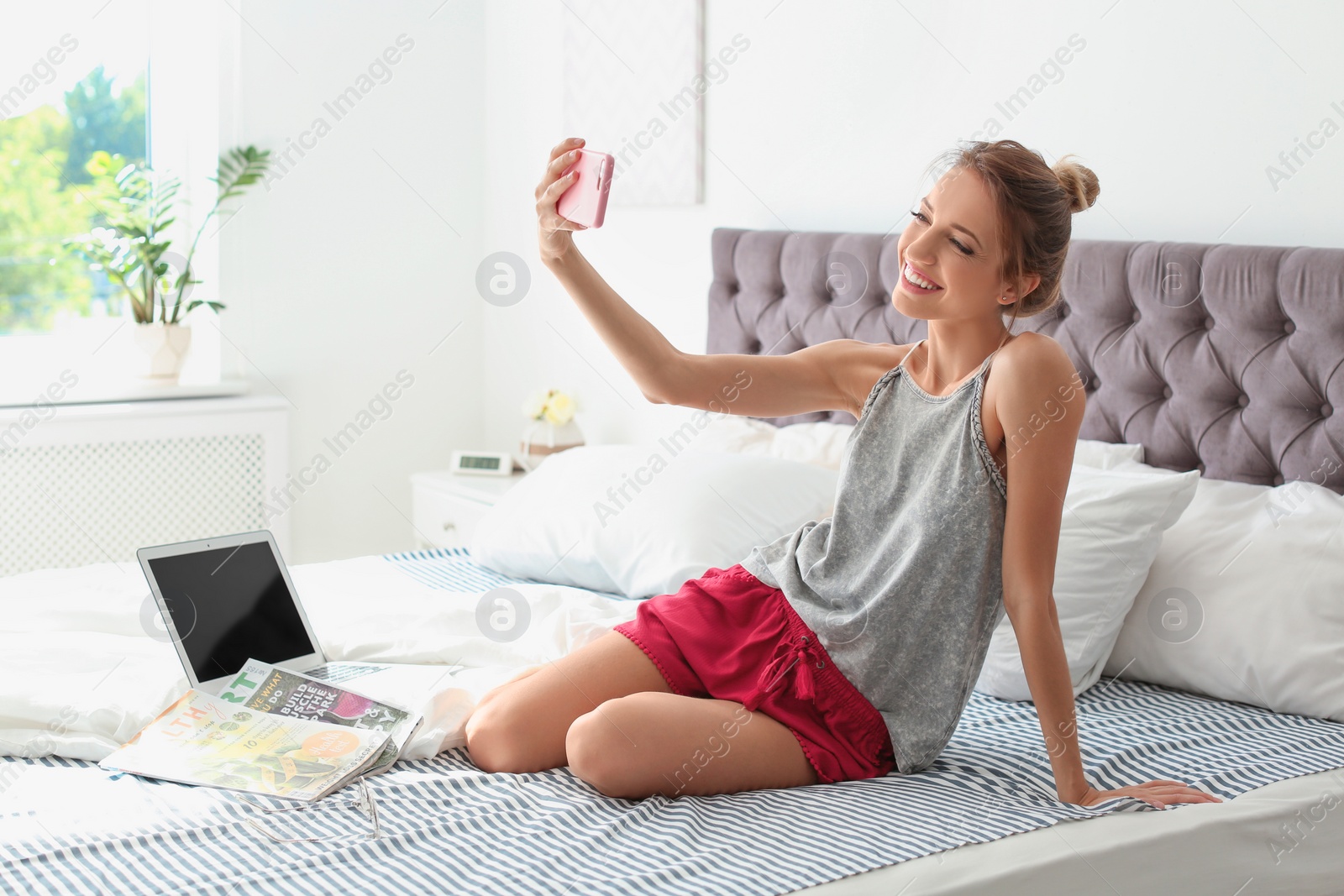 Photo of Beautiful young woman taking selfie in bed at home. Lazy morning