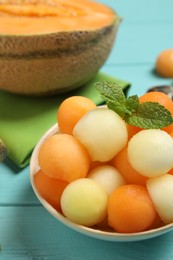 Melon balls and mint in bowl on light blue table, closeup