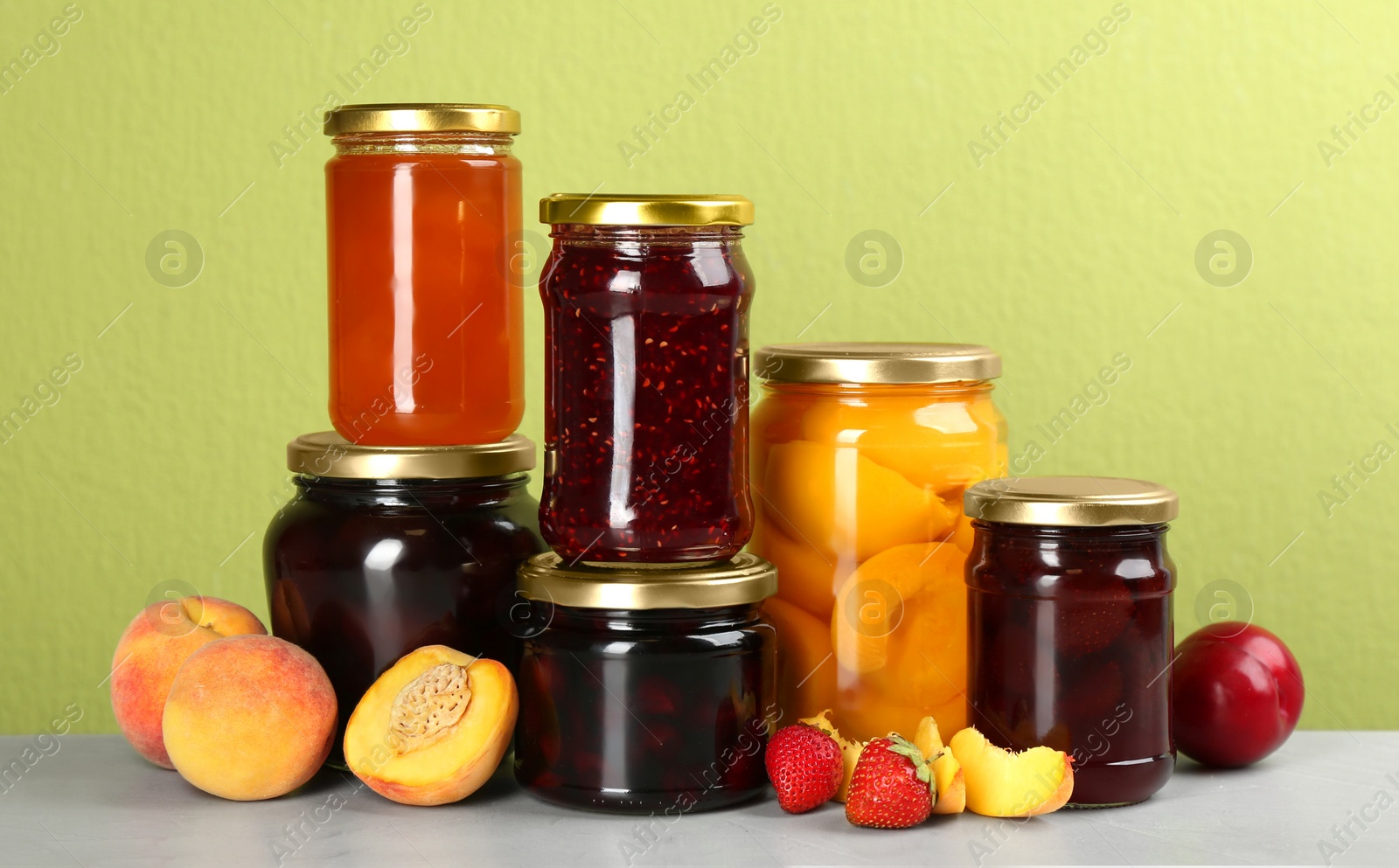Photo of Jars of pickled fruits and jams on light table