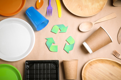 Photo of Recycling symbol, plastic, paper and wooden utensil on beige background, flat lay