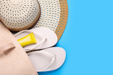 Photo of Straw hat, bag, sunscreen and flip flops on light blue background, flat lay and space for text. Beach accessories