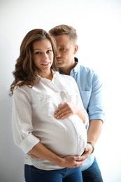 Photo of Pregnant woman with her husband on white background. Happy young family