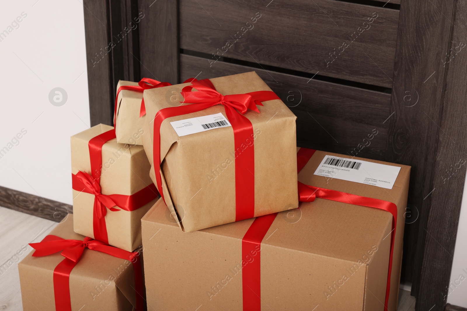 Photo of Christmas gift boxes near door indoors. Sending present by mail