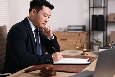 Photo of Notary writing notes at wooden table in office