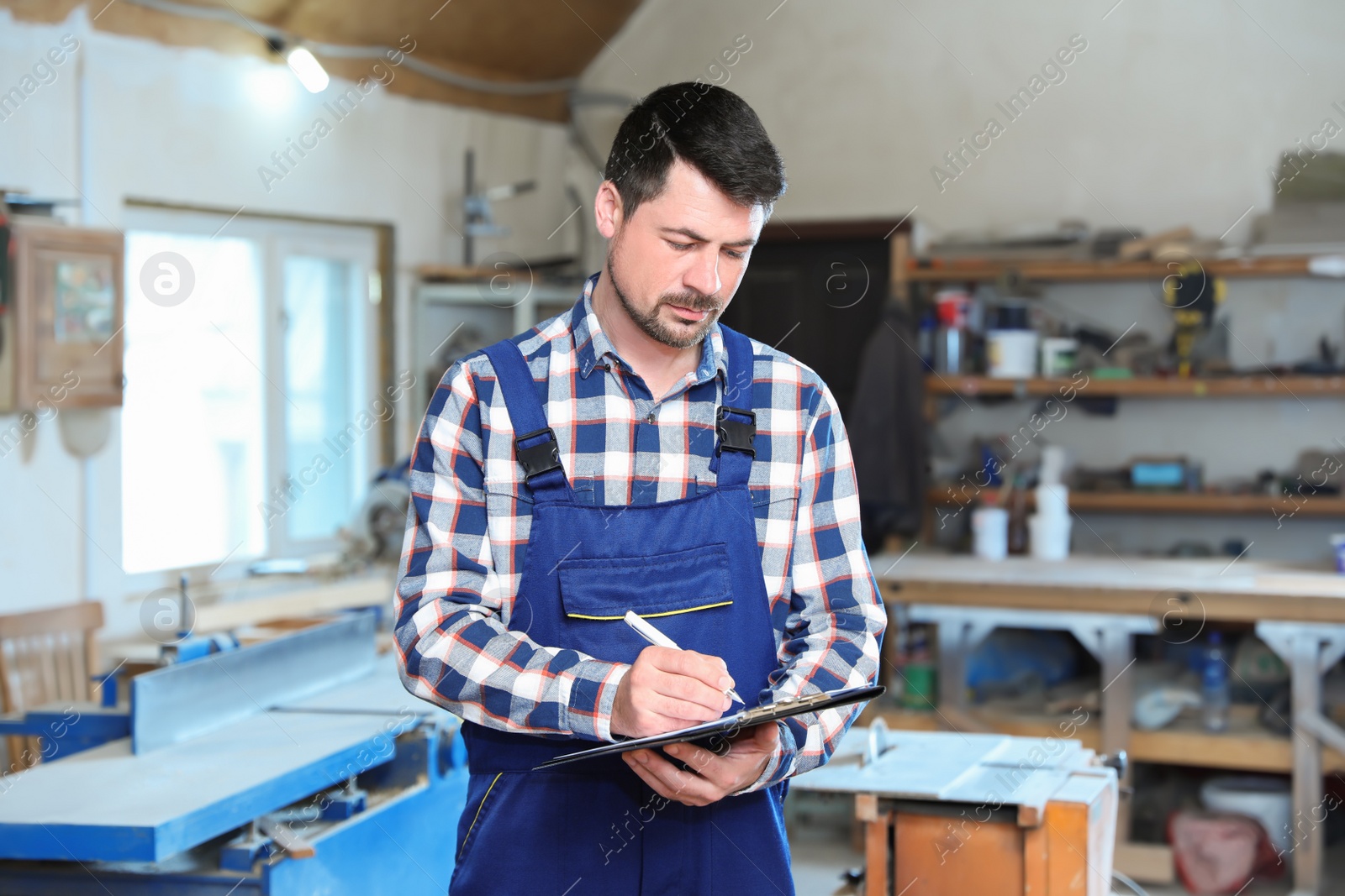 Photo of Mature working man in uniform taking order at carpentry shop