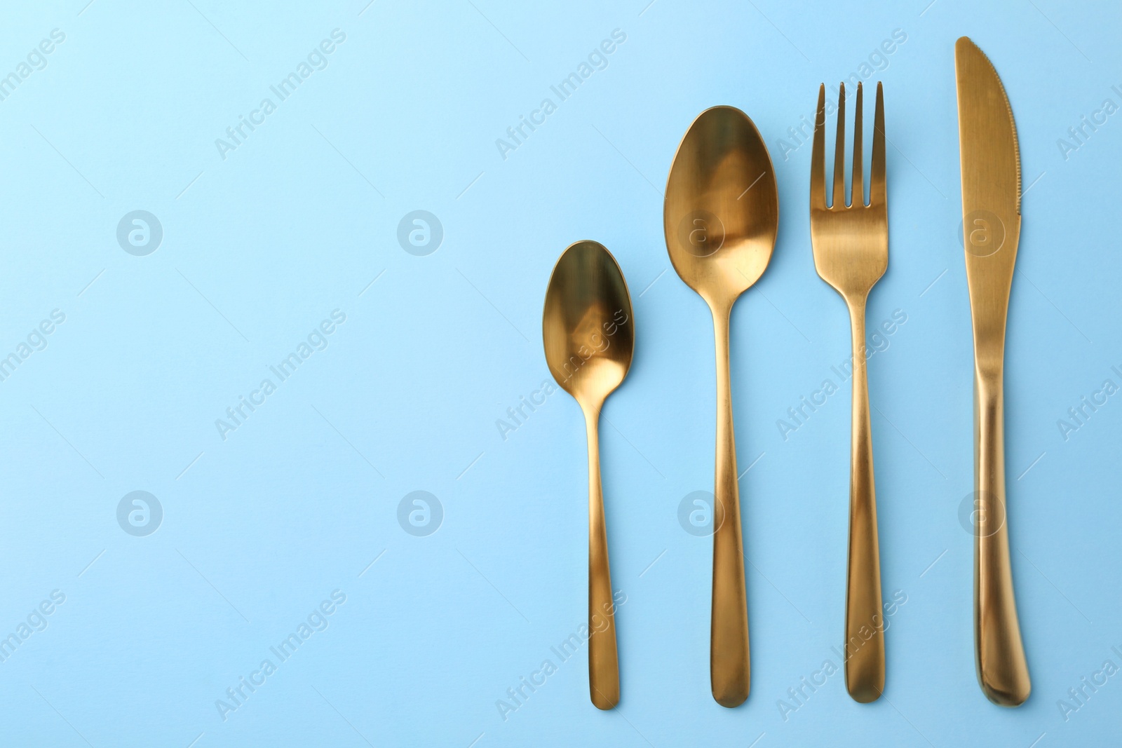 Photo of Stylish cutlery set on light blue table, flat lay. Space for text