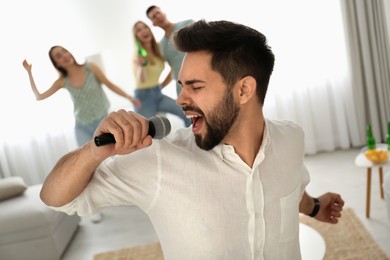 Young man singing karaoke with friends at home