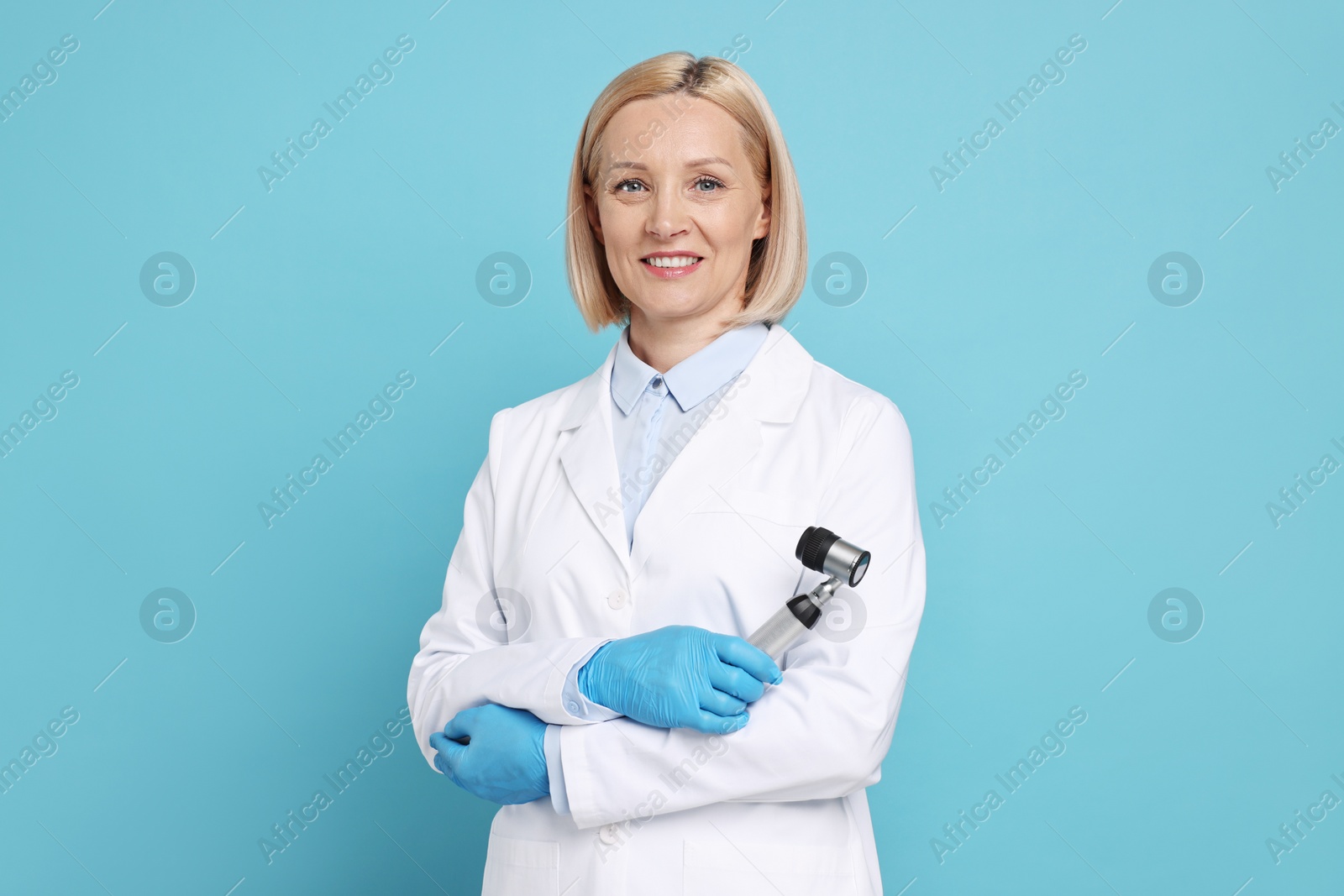 Photo of Happy dermatologist with dermatoscope on light blue background