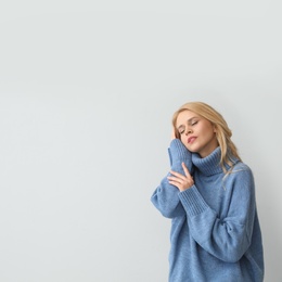 Beautiful young woman wearing warm blue sweater on light background. Space for text