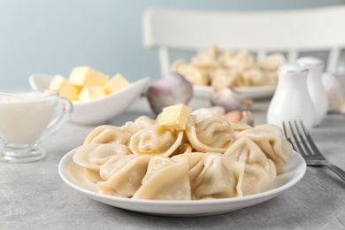 Photo of Tasty dumplings with butter on light grey table against blurred background