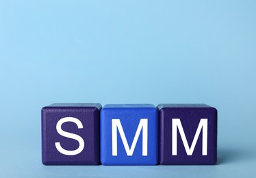 Photo of Colorful cubes with abbreviation SMM (Social media marketing) on light blue  background