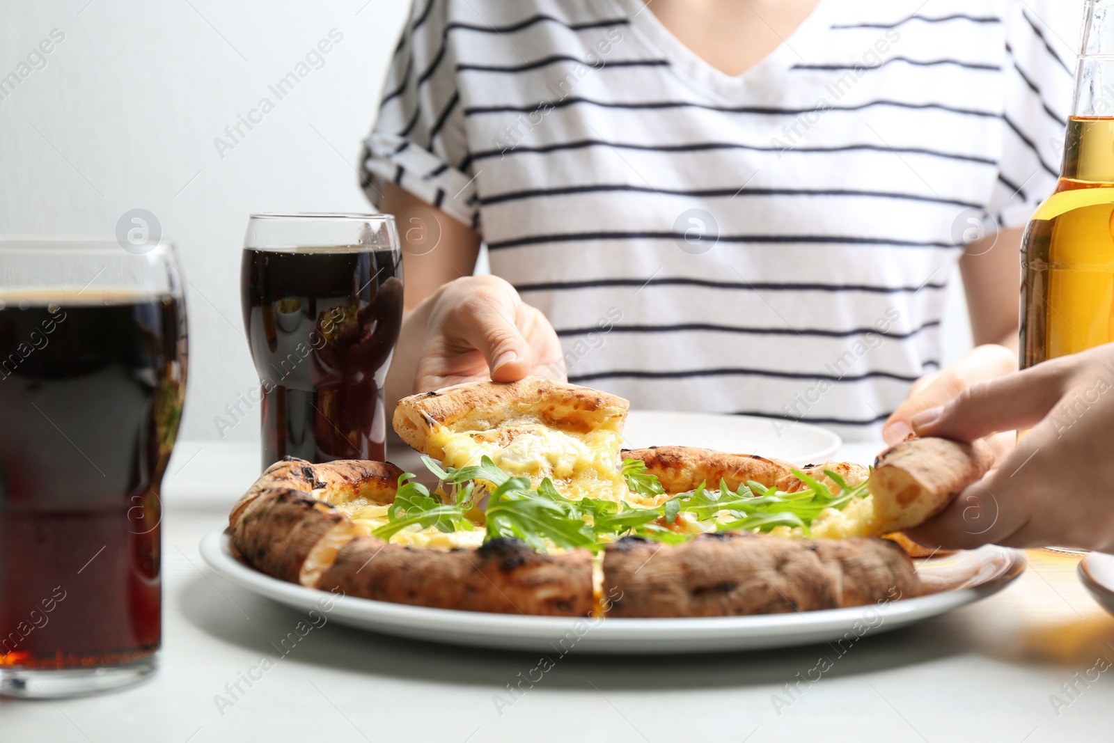 Photo of People taking pieces of delicious cheese pizza at white table, closeup