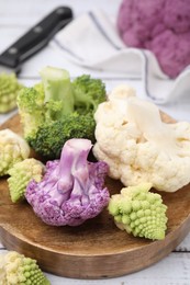 Various cauliflower cabbages on white wooden table, closeup