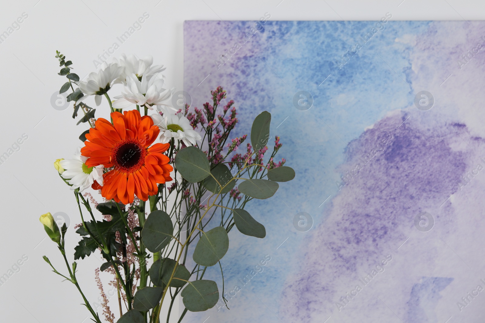 Photo of Stylish ikebana as house decor. Beautiful fresh flowers and eucalyptus branch near picture