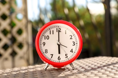 Red alarm clock on table outdoors at sunny morning