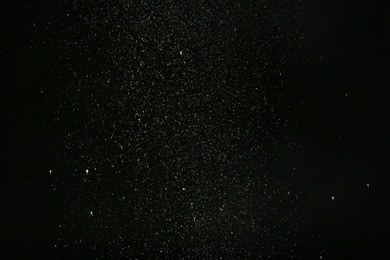 Photo of Snow flakes falling on black background. Winter weather