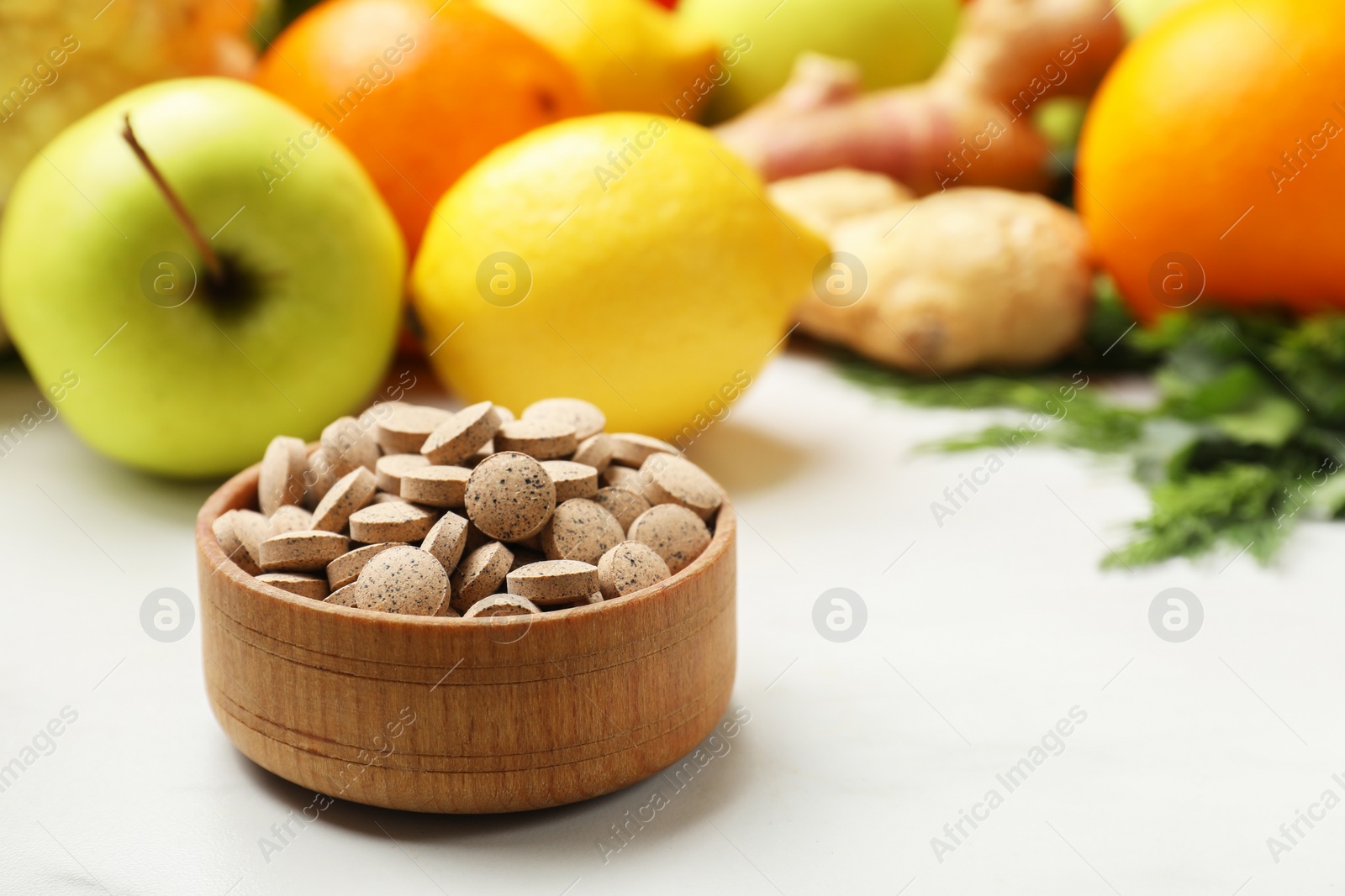 Photo of Dietary supplements in wooden bowl and products on white table, closeup. Space for text