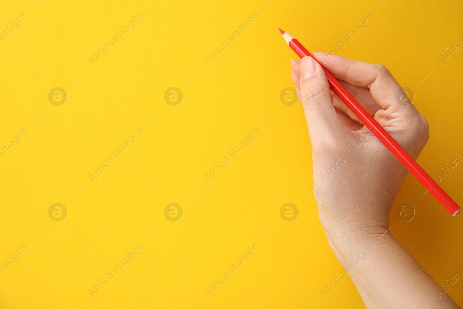 Photo of Woman with red pencil on yellow background, closeup. Space for text