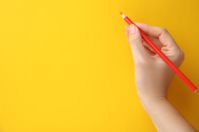 Woman with red pencil on yellow background, closeup. Space for text