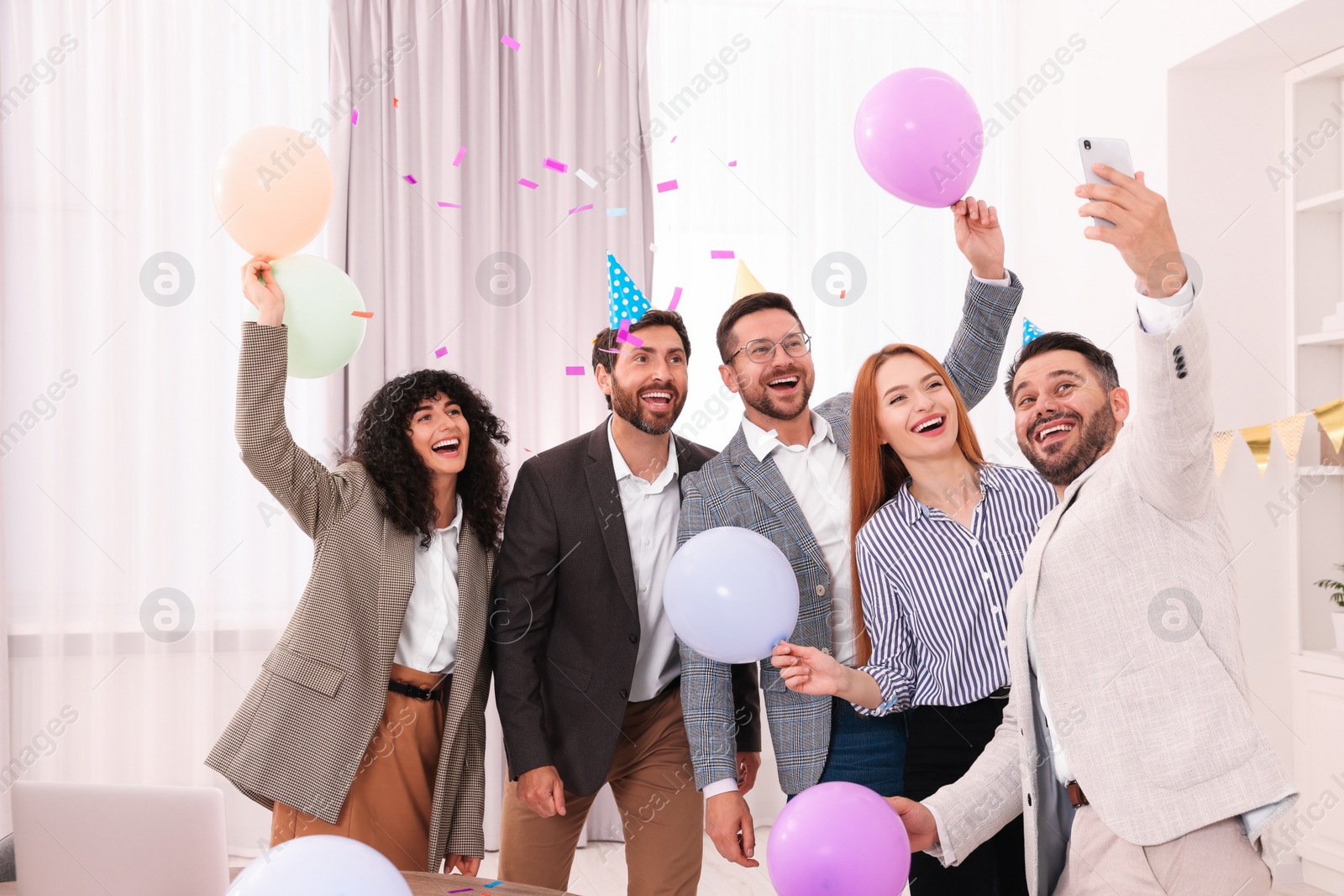 Photo of Coworkers taking selfie during office party indoors