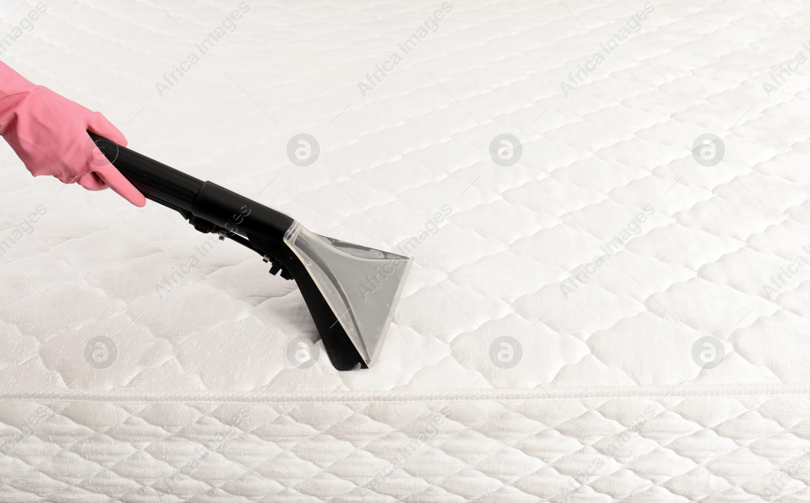 Photo of Person disinfecting mattress with vacuum cleaner, closeup. Space for text