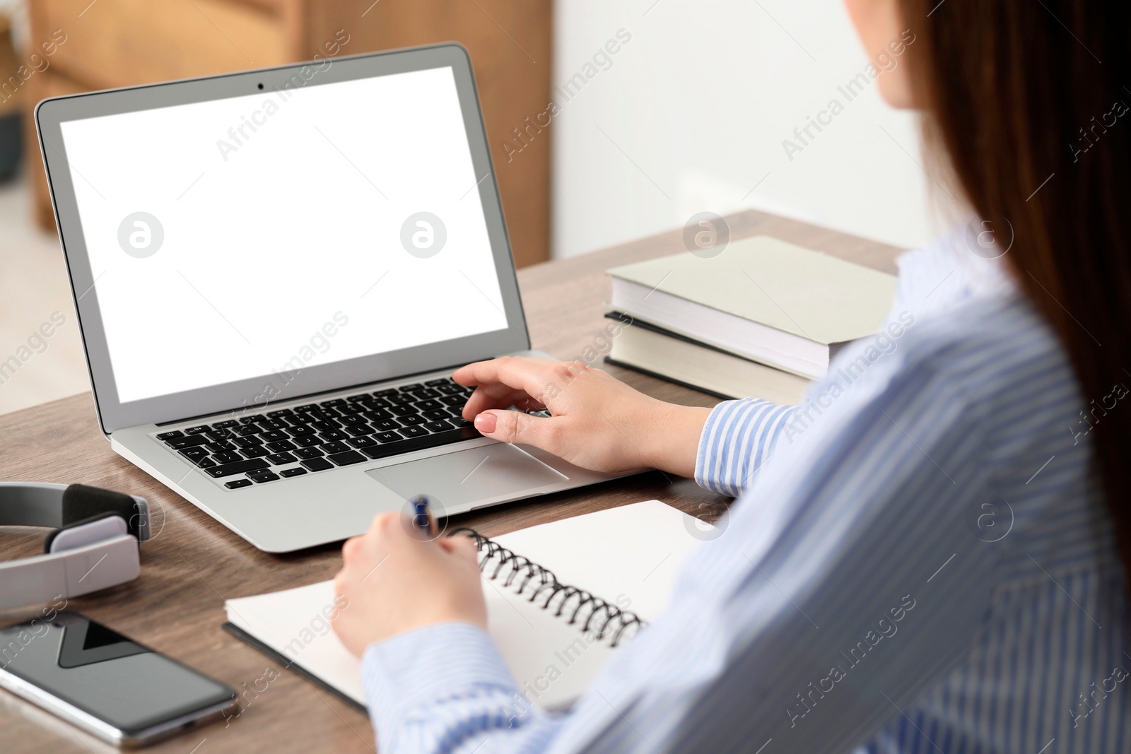 Photo of E-learning. Woman taking notes during online lesson at table indoors, closeup