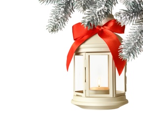 Christmas lantern with candle hanging on snowy fir tree branch against light background. Space for text