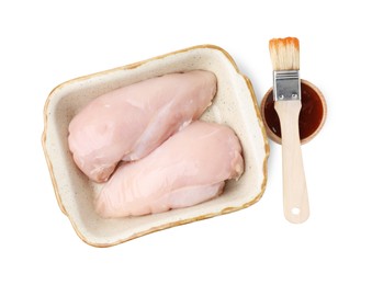 Photo of Marinade, basting brush, raw chicken fillets and chili peppers isolated on white, top view